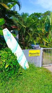 a surfboard sitting in the grass next to a fence at Nananuira Apartment and Room in Khao Lak