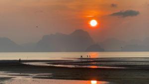 un grupo de personas caminando por la playa al atardecer en Koh Yao Seaview Bungalow en Ko Yao Noi