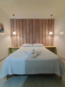 Un dormitorio con una cama blanca con dos velas. en Hotel Kasvel, en Valledupar