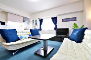 はなハウス 4F في غينوان: غرفة معيشة مع أريكة بيضاء ووسائد زرقاء