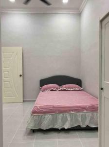 a bedroom with a bed with pink sheets and pillows at afza Homestay Paka A in Paka