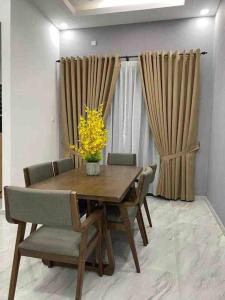 a dining room table with chairs and a vase of yellow flowers at afza Homestay Paka A in Paka