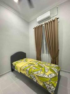 een slaapkamer met een bed met een gele sprei en een gordijn bij afza Homestay Paka A in Paka