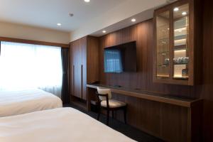a hotel room with a bed and a tv at Kadoya Hotel in Tokyo