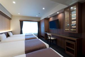 a hotel room with two beds and a television at Kadoya Hotel in Tokyo