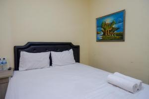 a bedroom with a white bed with a picture on the wall at Urbanview Hotel Jogja City Mall in Yogyakarta