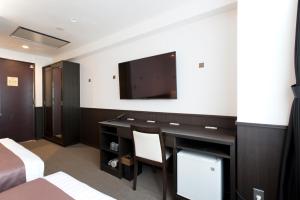a hotel room with a desk and a flat screen tv at Kadoya Hotel in Tokyo