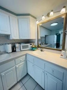 una cucina con armadi bianchi, lavandino e specchio di Daytona Beach Resort Oceanfront CondoStudio a Daytona Beach