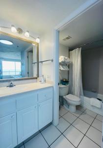 een badkamer met een wastafel, een toilet en een spiegel bij Daytona Beach Resort Oceanfront CondoStudio in Daytona Beach