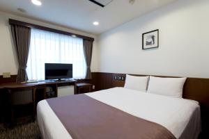 a hotel room with a bed and a television at Kadoya Hotel in Tokyo