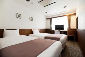 a hotel room with two beds and a television at Kadoya Hotel in Tokyo