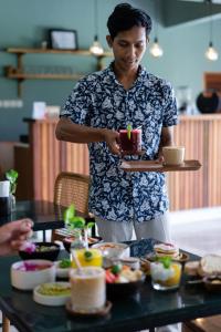 a man holding a tray with a cake on a table at Anchor Bed & Bread in Kuta Lombok