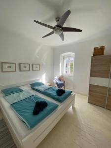 sypialnia z łóżkiem z niebieską pościelą i wentylatorem sufitowym w obiekcie Casa Grappa w miejscowości Mali Lošinj