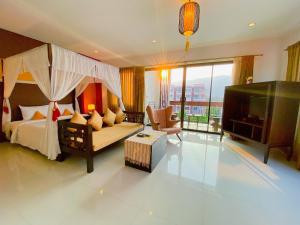 um quarto com uma cama, uma televisão e um sofá em The Empire Nimman em Chiang Mai