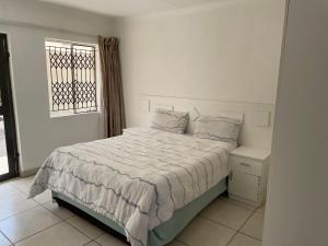 una camera da letto bianca con un letto e una finestra di La Fiance Village a Polokwane