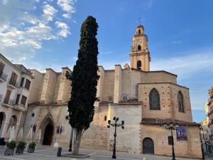 a church with a clock tower and a tree at La Iaia Maria in Gandía