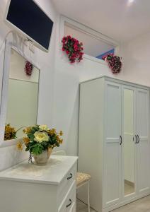 baño con un armario blanco con espejo y flores en Holiday house Lual en Agerola