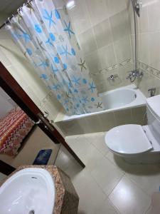 a bathroom with a toilet and a sink and a tub at Lovely 1-bedroom Apartment with free Parking on premises in Ajman 