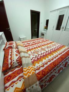 a large bed with a colorful blanket on it at Lovely 1-bedroom Apartment with free Parking on premises in Ajman 