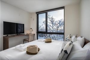 um quarto com uma cama branca com dois chapéus em Yotei Dream One by H2 Life em Niseko