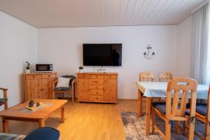 uma sala de estar com uma mesa e uma televisão na parede em Dünenhaus - Bungalow groß - zum Strand 50m em Ückeritz