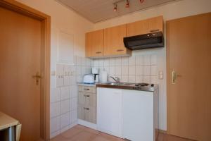 uma pequena cozinha com um lavatório e um balcão em Dünenhaus - Bungalow groß - zum Strand 50m em Ückeritz