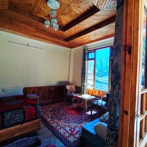 a living room with a bed and a table and window at Alpine Homestay at Gadagusain in Banjār