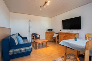 Una sala de estar con un sofá azul y un televisor de pantalla plana. en Dünenhaus - Bungalow groß - zum Strand 50m, en Ückeritz 6 fotos más