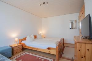 um pequeno quarto com uma cama e uma televisão em Dünenhaus - Bungalow groß - zum Strand 50m em Ückeritz