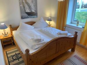 um quarto com uma cama de madeira com lençóis e almofadas brancos em Ferienwohnung Deichläufer em Nordstrand