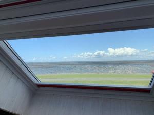 a window in a house with a view of the ocean at Ferienwohnung Frische Brise in Nordstrand