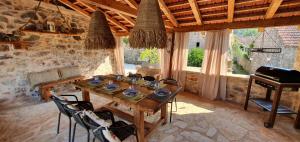 a dining room with a wooden table and a piano at Hvar Stone Villa with pool in Vrbanj