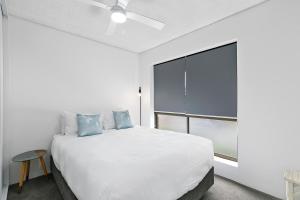 a white bedroom with a large bed and a window at Beachwood at Margate Beach in Redcliffe