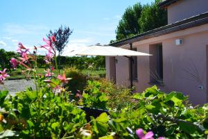 - un parasol blanc dans un jardin fleuri dans l'établissement Le Stanze di Bacco, à Monteveglio