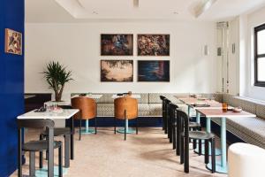 a dining room with tables and chairs and paintings on the wall at Hôtel Rosalie in Paris