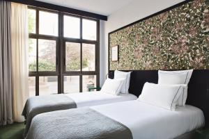two beds in a hotel room with a large window at Hôtel Rosalie in Paris
