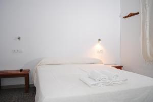 a white bed with two white towels on it at Hostal Paris Ciutadella in Ciutadella