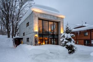 a building covered in snow in front at Yuki Uchi by H2 Life in Niseko