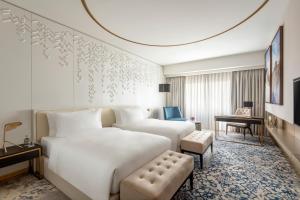 a hotel room with a large white bed and a chair at Steigenberger Hotel Doha in Doha