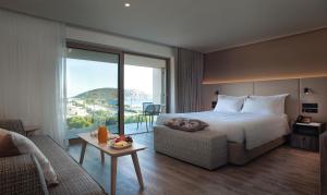a hotel room with a large bed and a couch at Vincci EverEden in Anavyssos