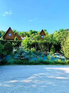 un jardin avec un étang et des maisons en arrière-plan dans l'établissement Domki nad Soliną CZARNY KOT 509-797-777, à Solina