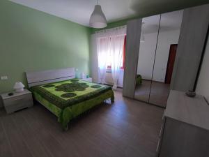 a green bedroom with a bed and a mirror at CASA VACANZE My Way in Cavo