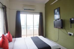 a bedroom with a bed with a tv and a window at Sorrento Homes in Pune