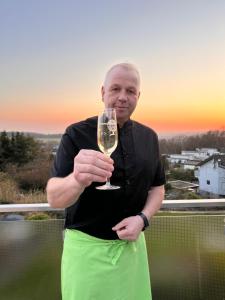 Ein Mann hält ein Glas Wein. in der Unterkunft Landhotel Fernblick in Hümmerich