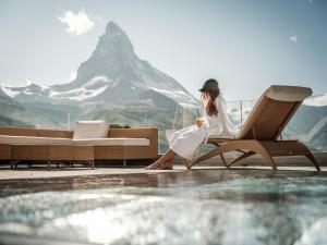 a woman sitting on a chair next to a pool at Riffelalp Resort 2222m - Ski-in & Ski-out in Zermatt
