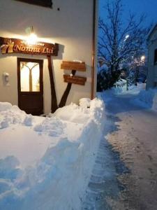 a building covered in snow next to a street at Agriturismo NONNU LUI` in Amandola