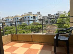 uma varanda com uma cadeira e vista para os edifícios em Backpackershostel em Pune