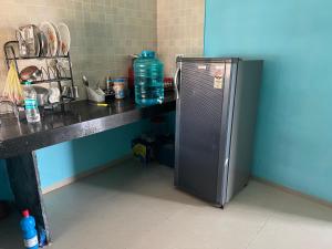 a kitchen with a refrigerator next to a counter with water bottles at Backpackershostel in Pune
