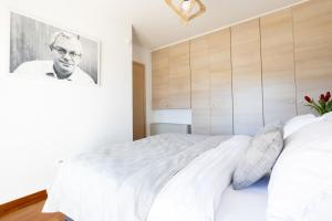 um quarto com uma cama branca e um retrato de um homem em Athenian Riviera Maisonette, Varkiza, 7min walk from Beach Park em Vári