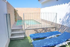 una piscina con 2 sillas azules en el balcón en Bungalow La Roa I, en Conil de la Frontera